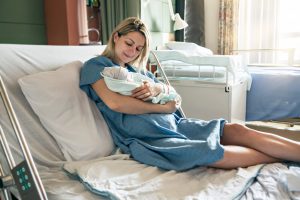 Young mother in hospital bed with new born baby